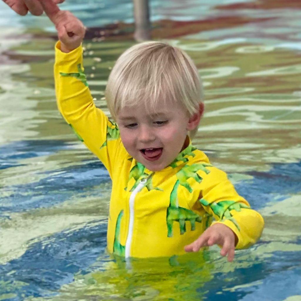 Boy in Pool Wearing Fluro Dinosaurs Unisex Long Sleeve Zip Swimmers