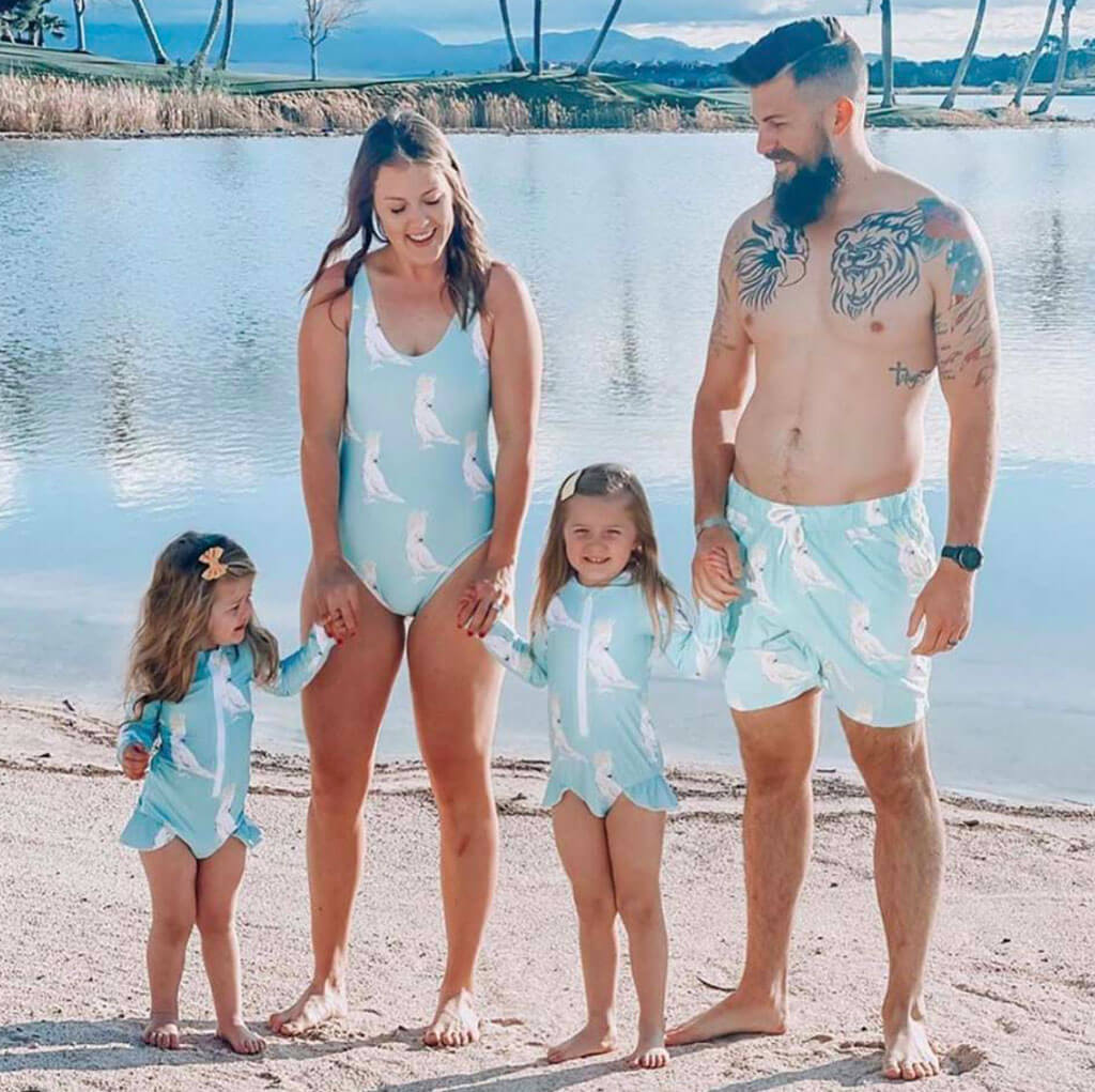 Man Wearing Green Cockatoo Men's Boardshorts On Beach With Family