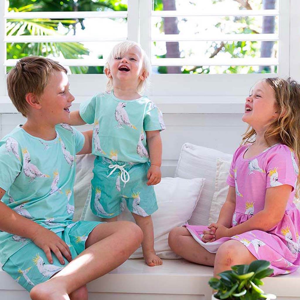 Girl Wearing Pink Cockatoo Short Sleeve Pocket Dress  While Sitting And Laughing With Two Boys