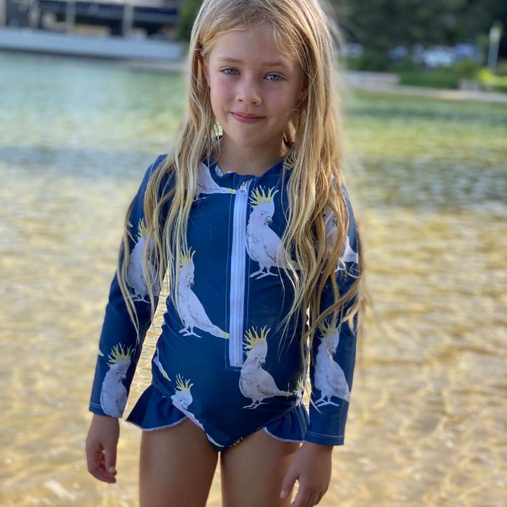 Girl On Beach Wearing Navy Cockatoo Girls Long Sleeve Zip Swimmers