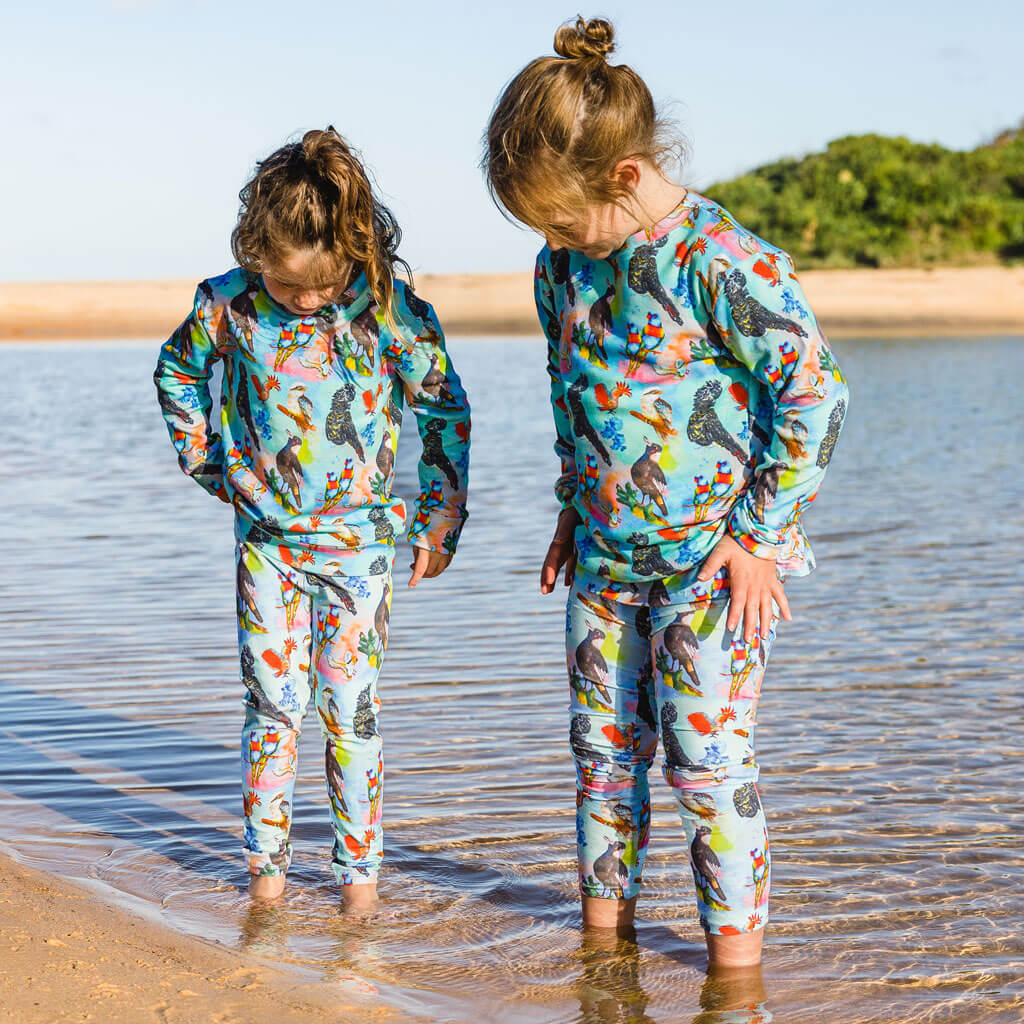 Two Girls Wearing Feathered Friends Kids' Leggings While Standing In Water