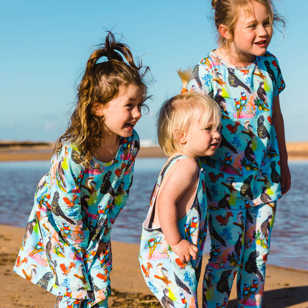 Girl Wearing Feathered Friends Long Sleeve Pocket Dress While With Siblings In Matching Print