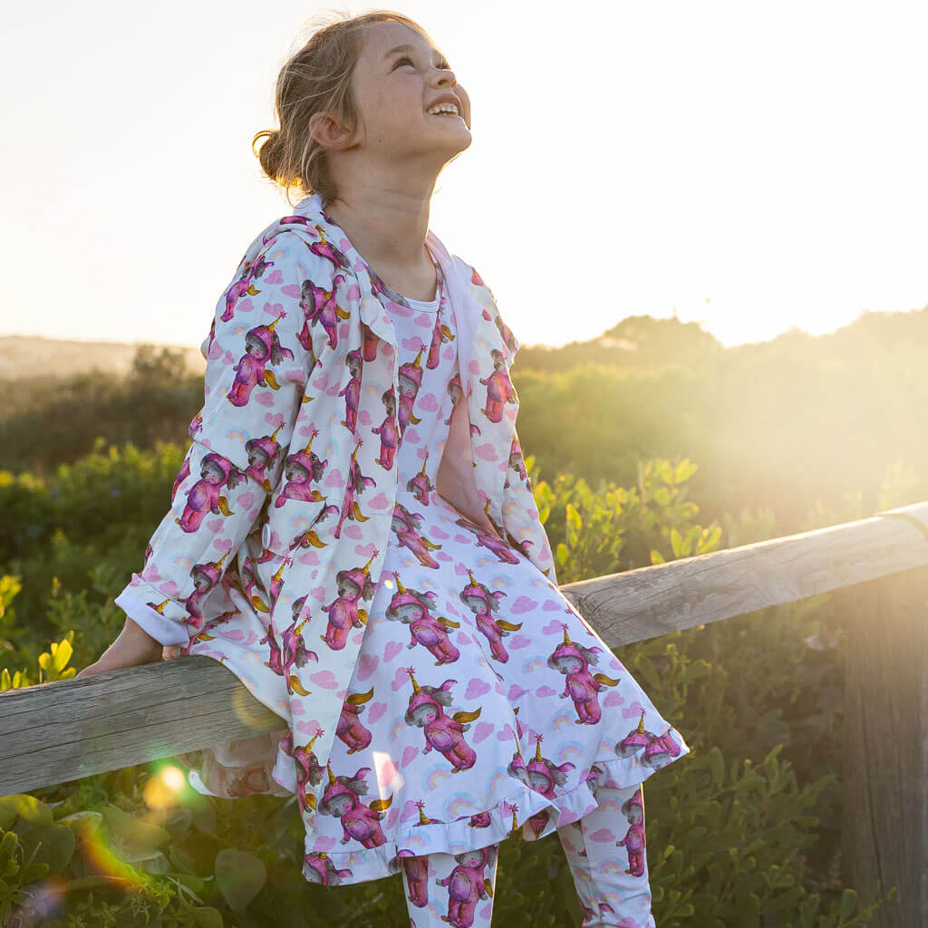 Girl Sitting On Fence Wearing Unicorn Koala Raincoat