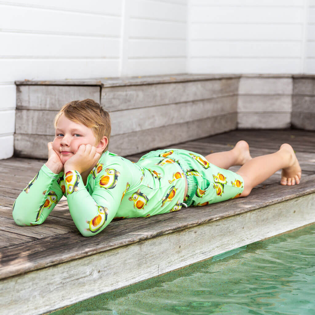 Boy Wearing Avocado Koala Kids' Rash Top While Laying On Deck