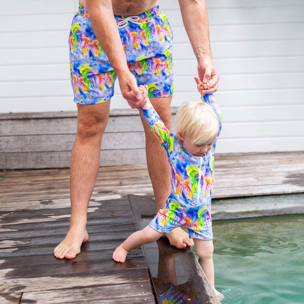 Man Wearing Fluro Jellyfish Men's Boardshorts While Poolside With Toddler