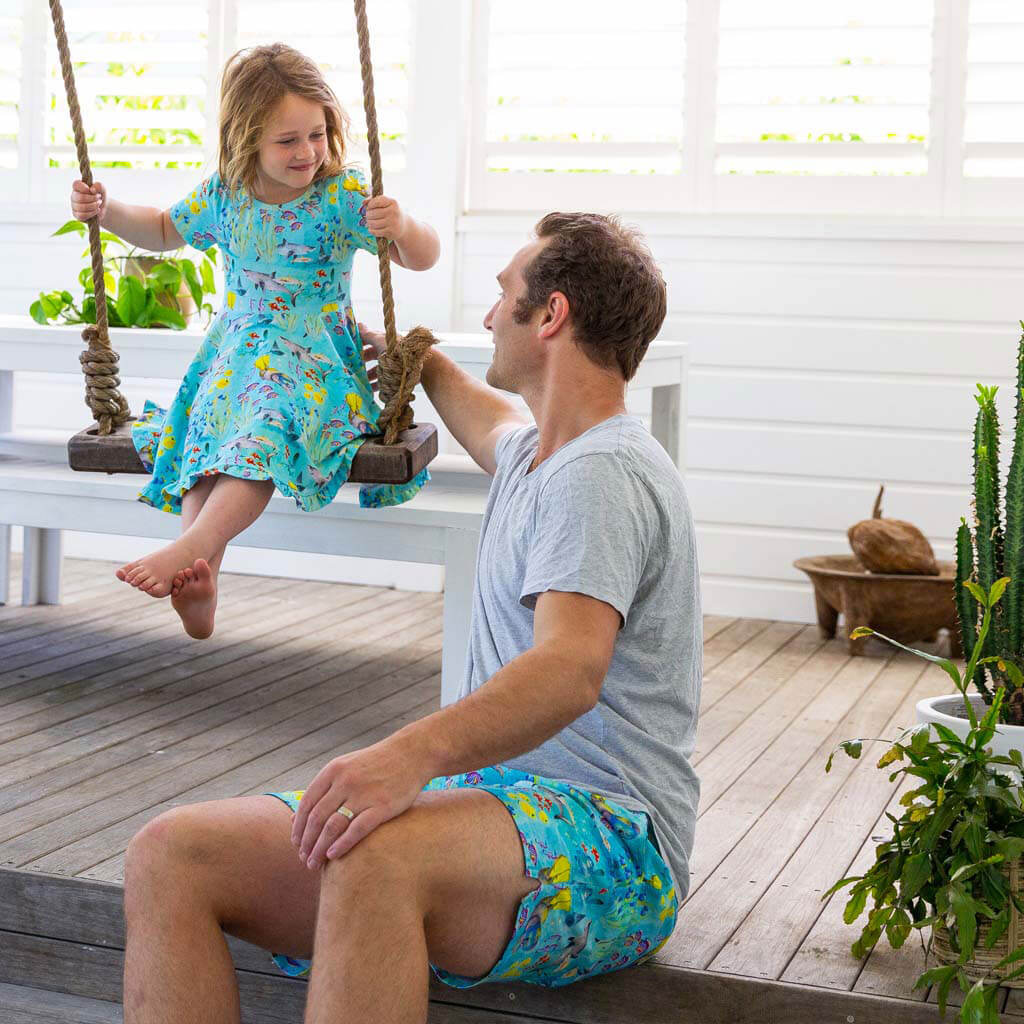 Dad Wearing Great Barrier Reef Men's Boardshorts While Pushing Girl On Swing