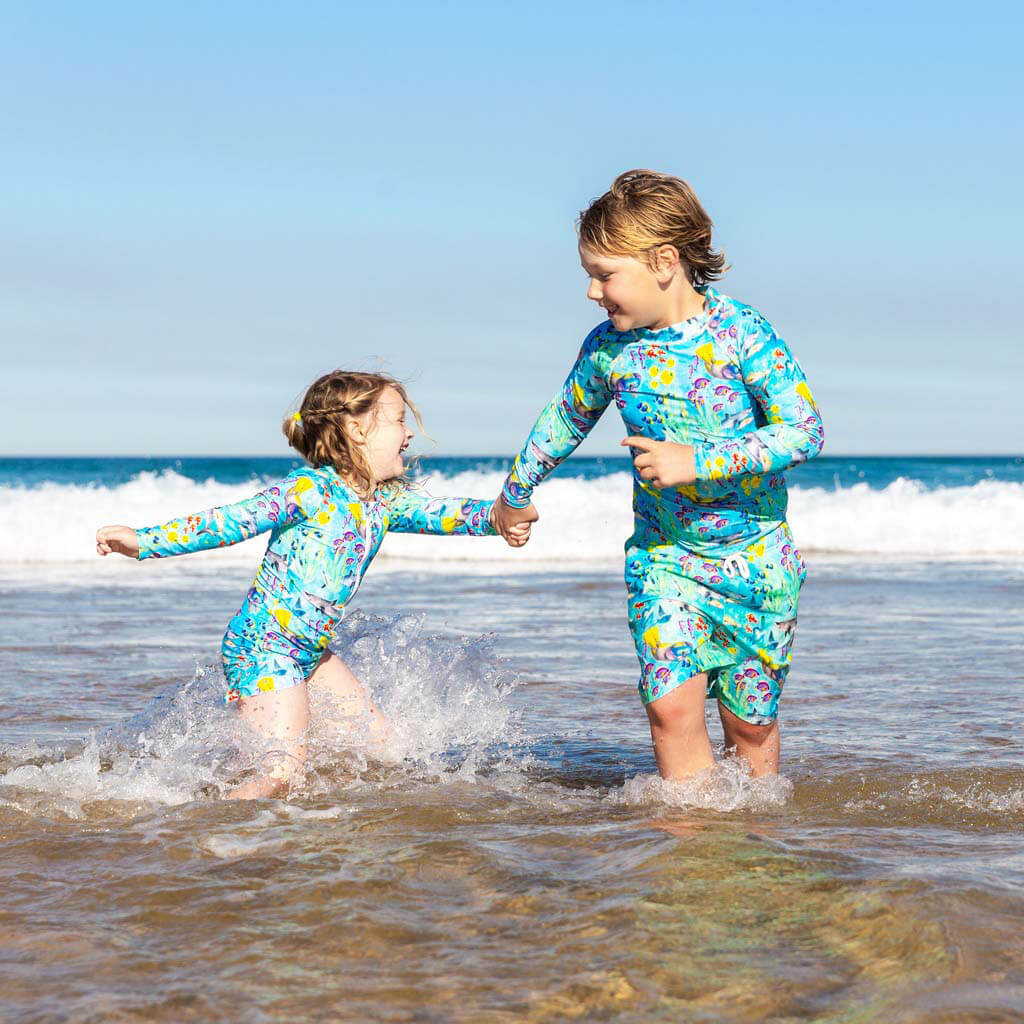 Smiling Boy Running In Waves At Beach With Girl Wearing Great Barrier Reef Kids' Rash Top