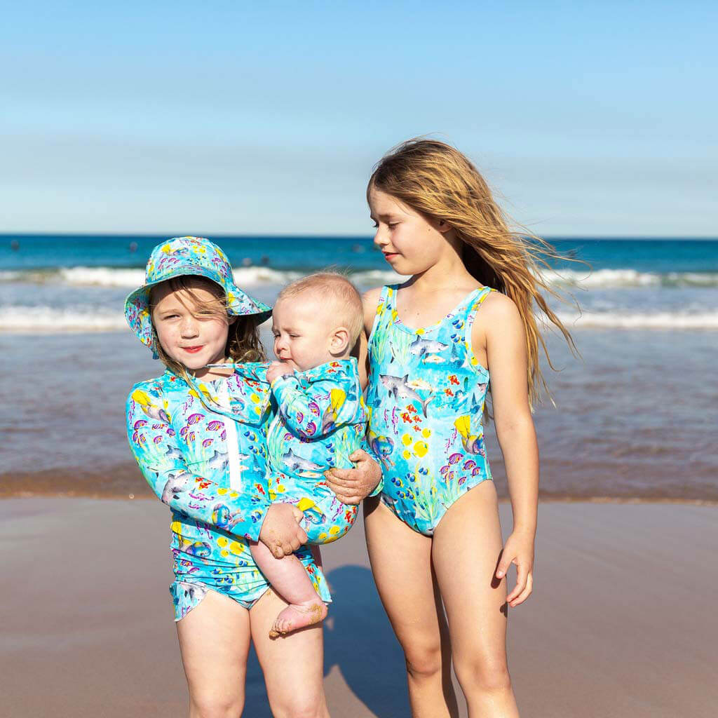 Girl On Beach Wearing Great Barrier Reef Girls Sleeveless Swimsuit With Siblings