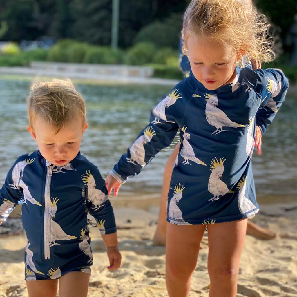 Two Little Girls On Beach Wearing Navy Cockatoo Kids' Rash Top