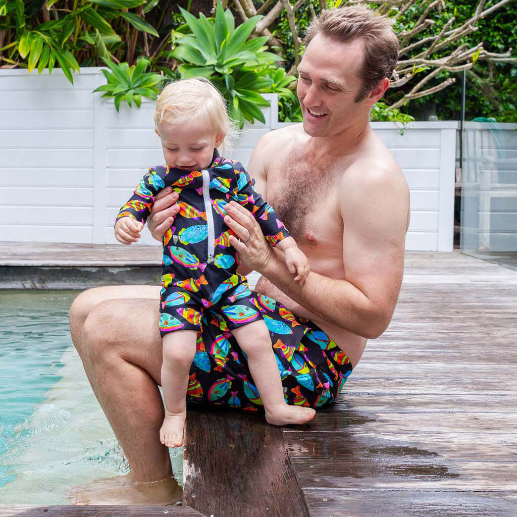 Toddler Wearing Neon Fish Unisex Long Sleeve Zip Swimmers With Dad Poolside 