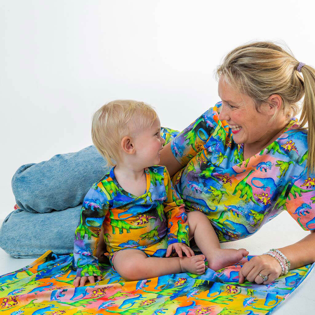 Baby Sitting On Mat With Mum While Wearing Rainbow-saurus Long Sleeve Onesie